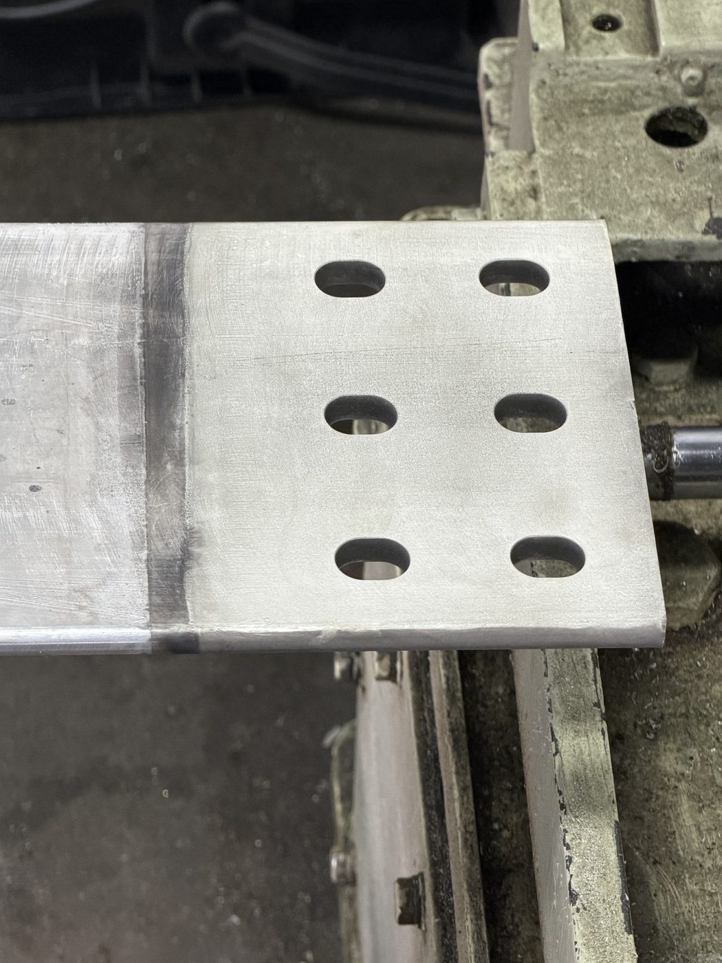 Close-up of an aluminum generator bus bar end pad in the Southern Switch machine shop — freshly machined contact surface with bolt pattern.