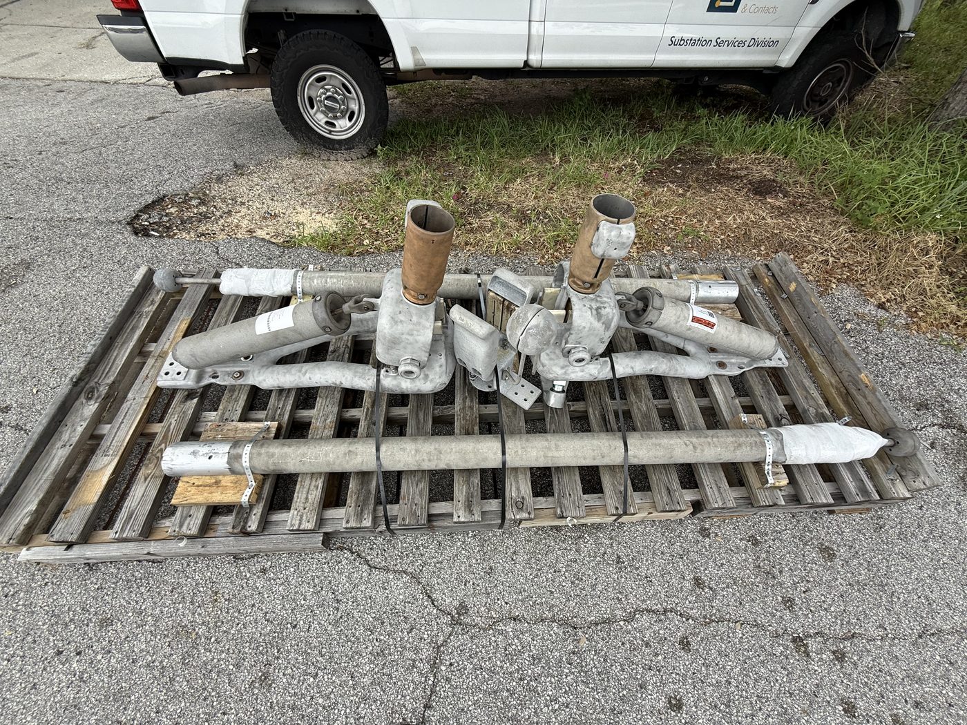 Two Southern States EV1 disconnect switches on a pallet at Southern Switch — the unit on the right has a new machined arm, visibly brighter aluminum compared to the original.
